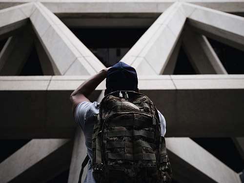 san francisco person wearing shirt and hiking bag looking in front of grey concrete structure while standing during daytime triangle